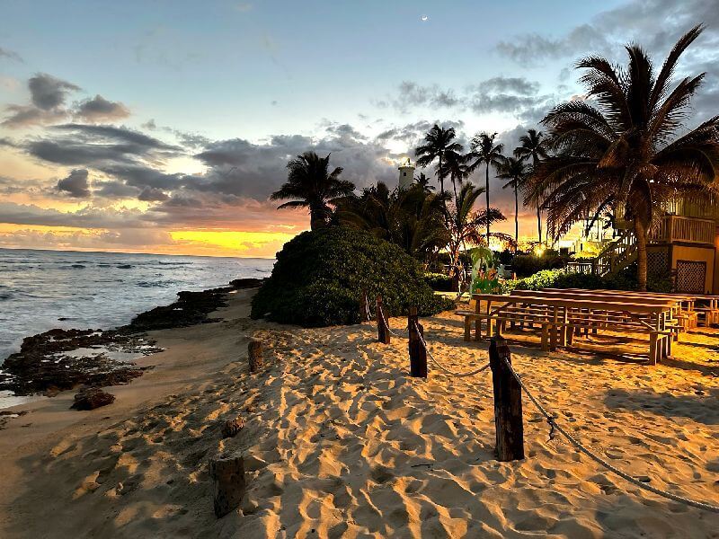 The Germaine's Luau Beach Sunset provides a picturesque and serene backdrop for guests to witness the stunning Hawaiian sunset during the cultural festivities at Germaine's Luau in Kapolei, Hawaii.