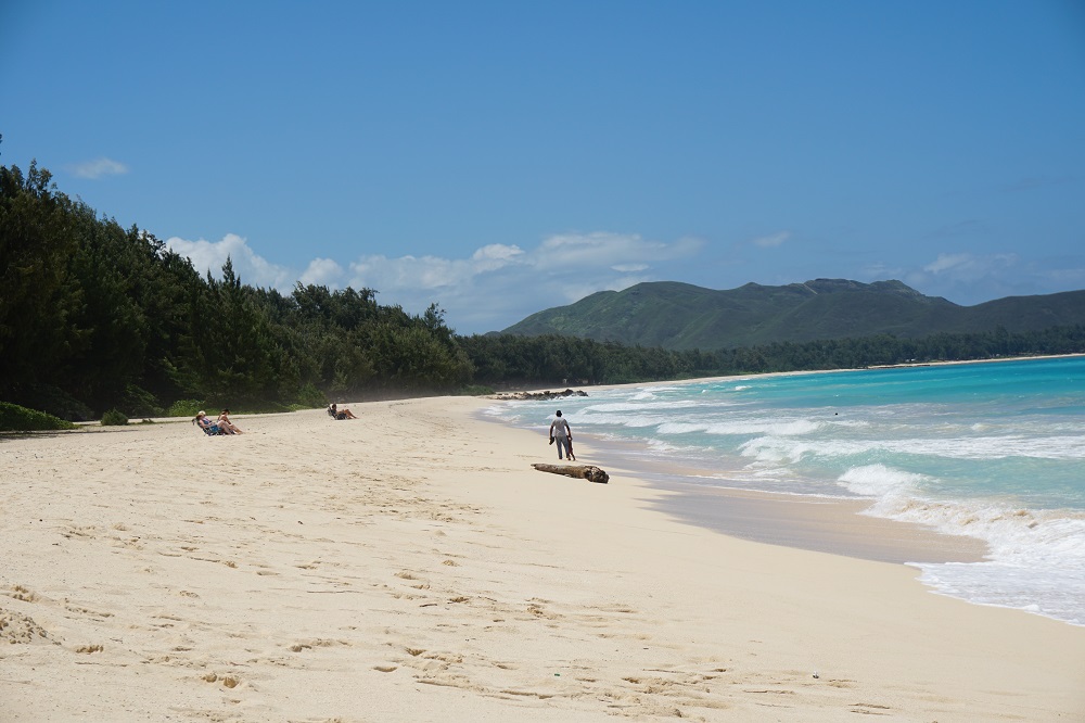 A breathtaking view of Waimanalo Bay, located on the eastern coast of Oahu, Hawaii. This pristine bay boasts turquoise waters, soft sandy beaches, and a backdrop of majestic mountains, offering a serene and picturesque setting for beachgoers and nature lovers to enjoy.